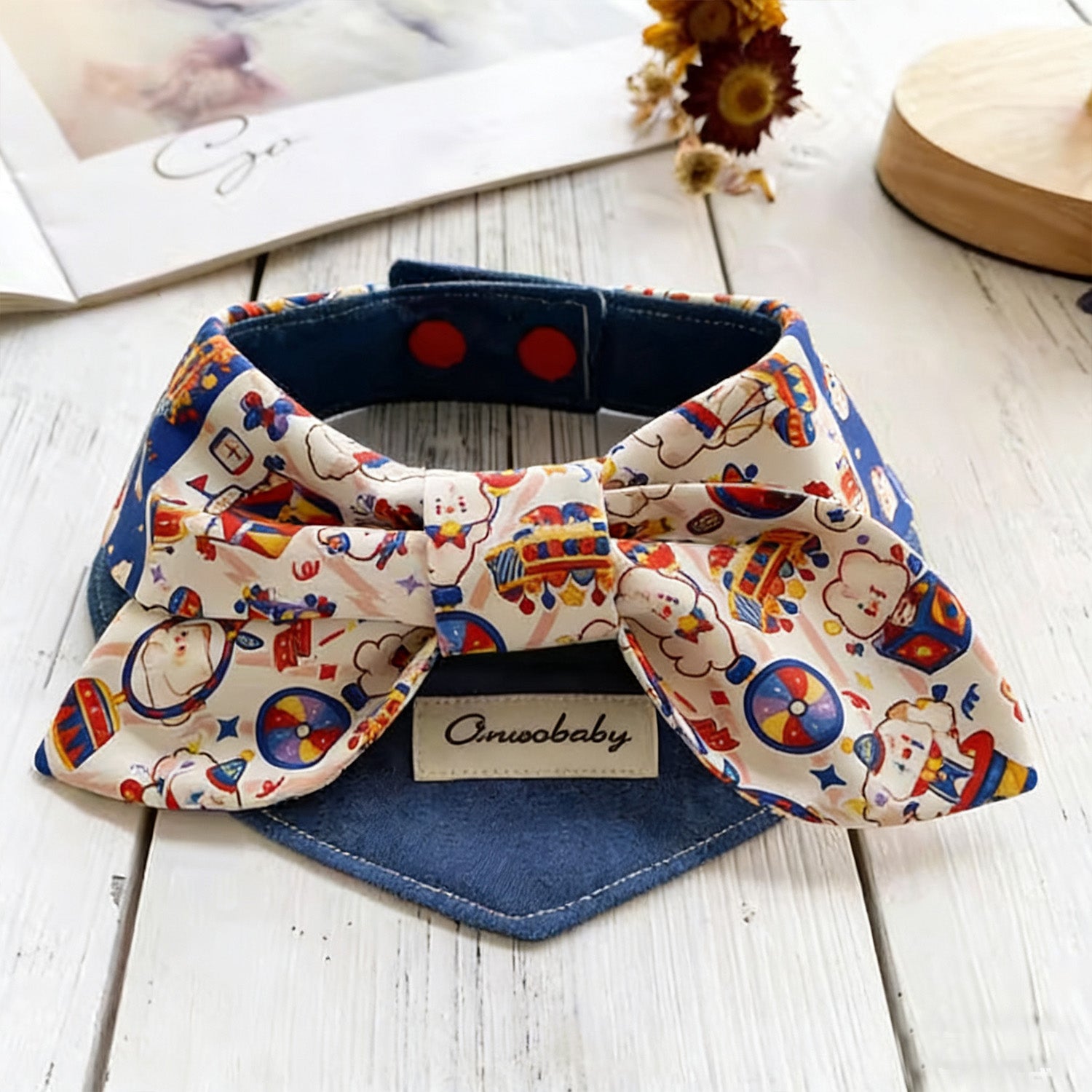 Top view of circus-themed bow pet collar with snap-button closure and denim base