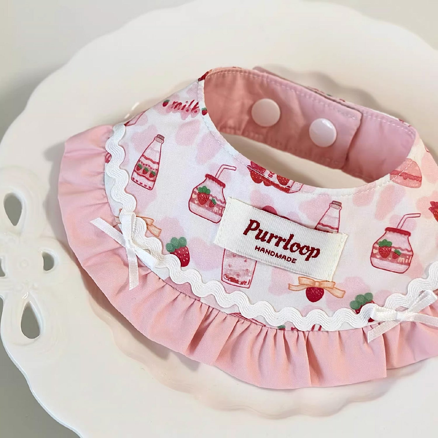Pastel pink strawberry milk pet bandana collar styled on lace plate