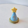 Load image into Gallery viewer, Blue felt cone birthday party hat with number one emblem and yellow star on top close up on white background
