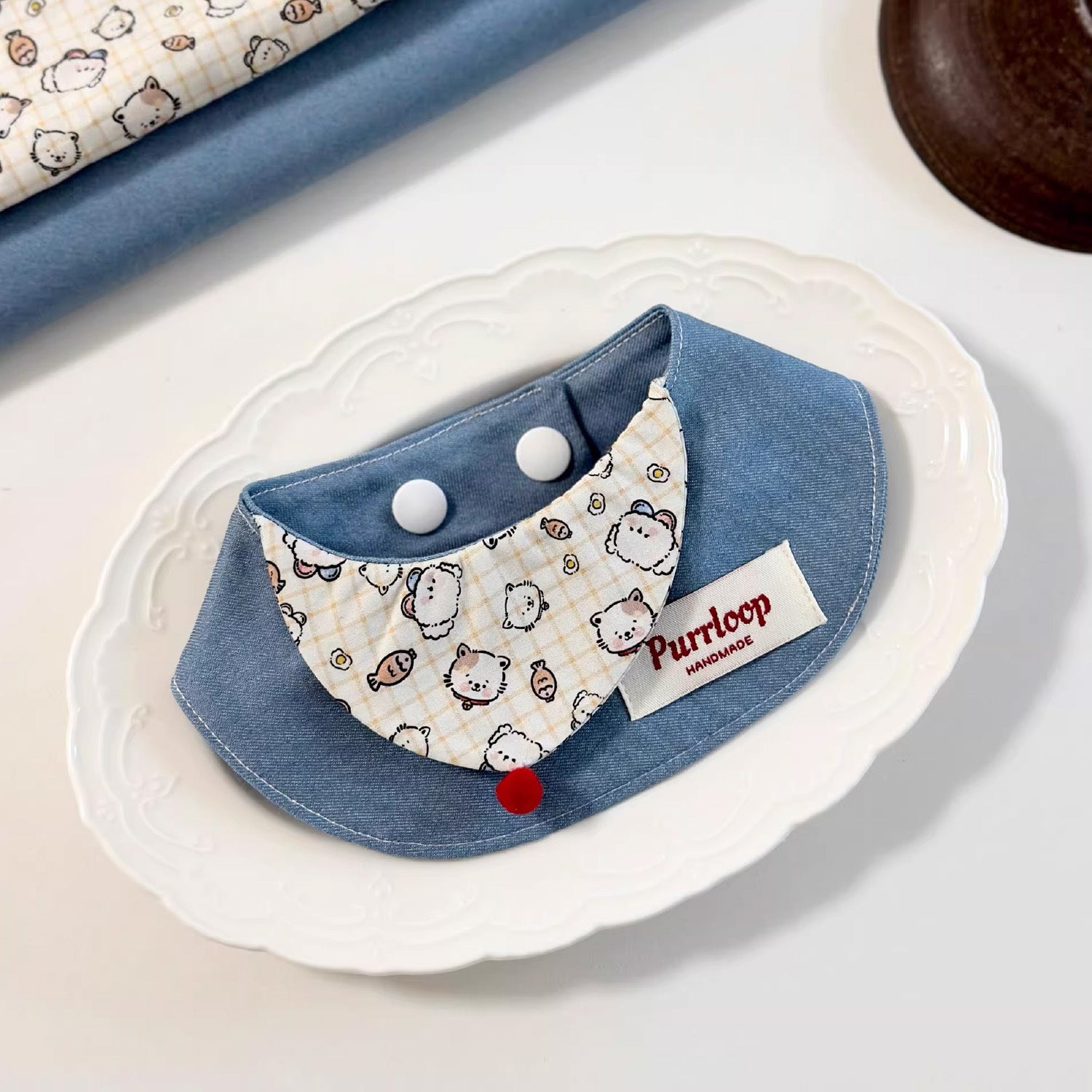 Playful cartoon print denim pet collar bandana on white decorative plate