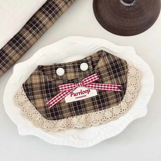 Vintage brown plaid pet collar with lace trim and pink bow on white plate