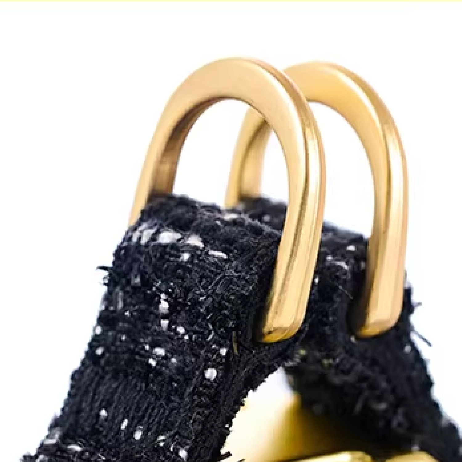 Close-up of gold D-ring hardware on black tweed dog harness