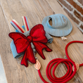 Load image into Gallery viewer,  GraviPaw denim cat harness with red bow, matching red leash and denim hat laid flat on wooden table
