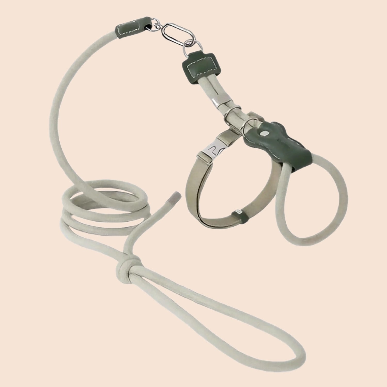 Beige lightweight adjustable cat harness and soft rope leash set coiled flat on white background with metal hardware
