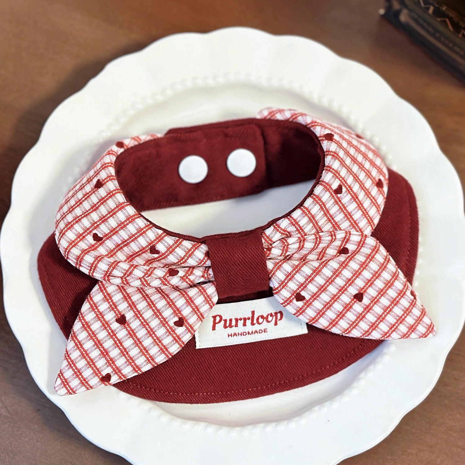 Wine red structured pet collar with red gingham plaid bow on white plate