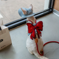 Load image into Gallery viewer, Slim white cat wearing GraviPaw denim harness with red bow standing in front of mirror
