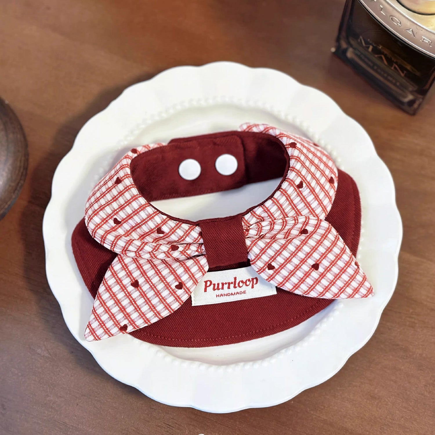 Top view of wine red plaid bow pet collar bandana on white decorative plate