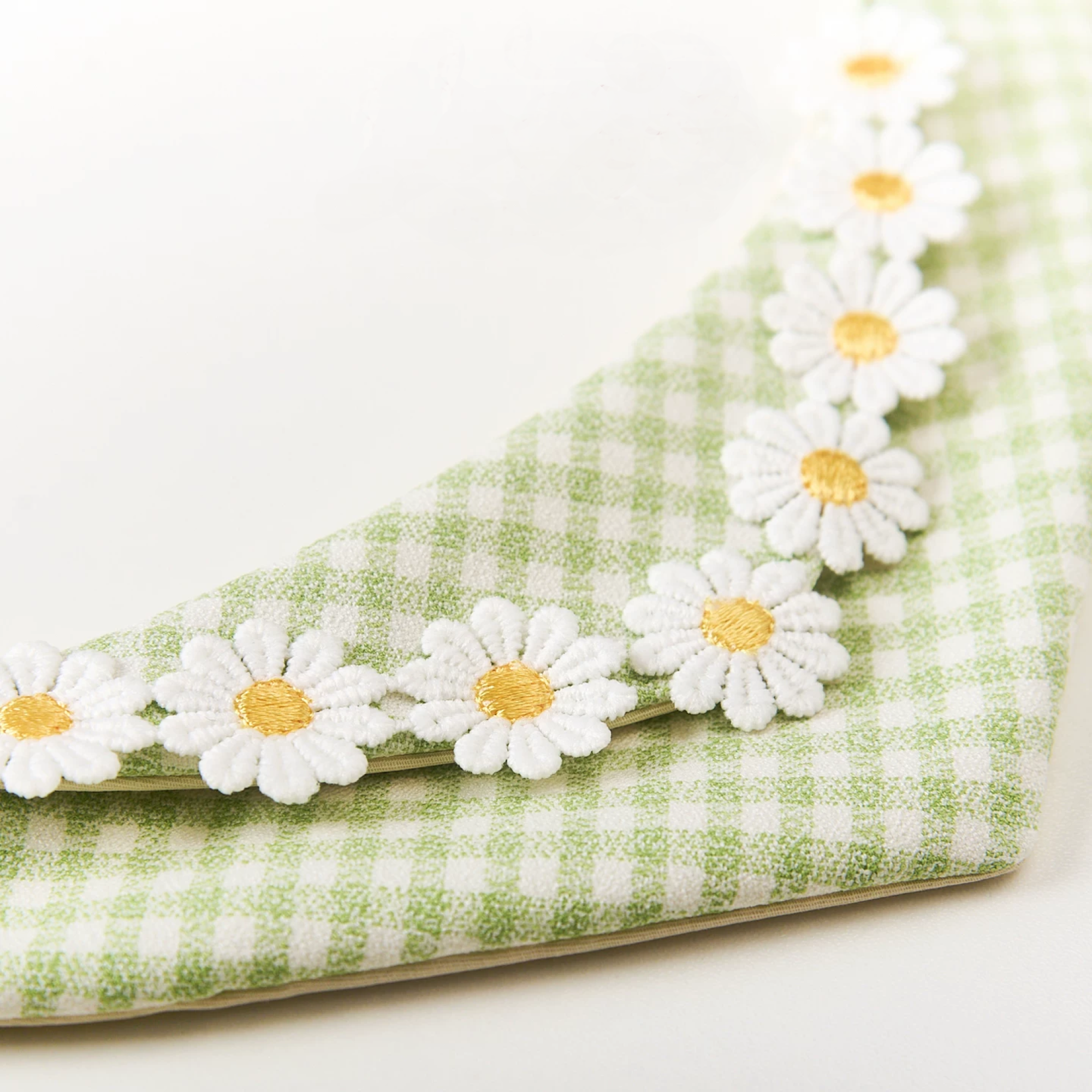 Side view of green daisy pet bandana showing cotton-linen fabric texture and embroidered floral trim