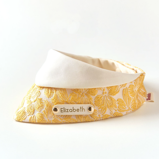Side angle of gold floral pet bandana showing jacquard texture and personalized engraved name tag